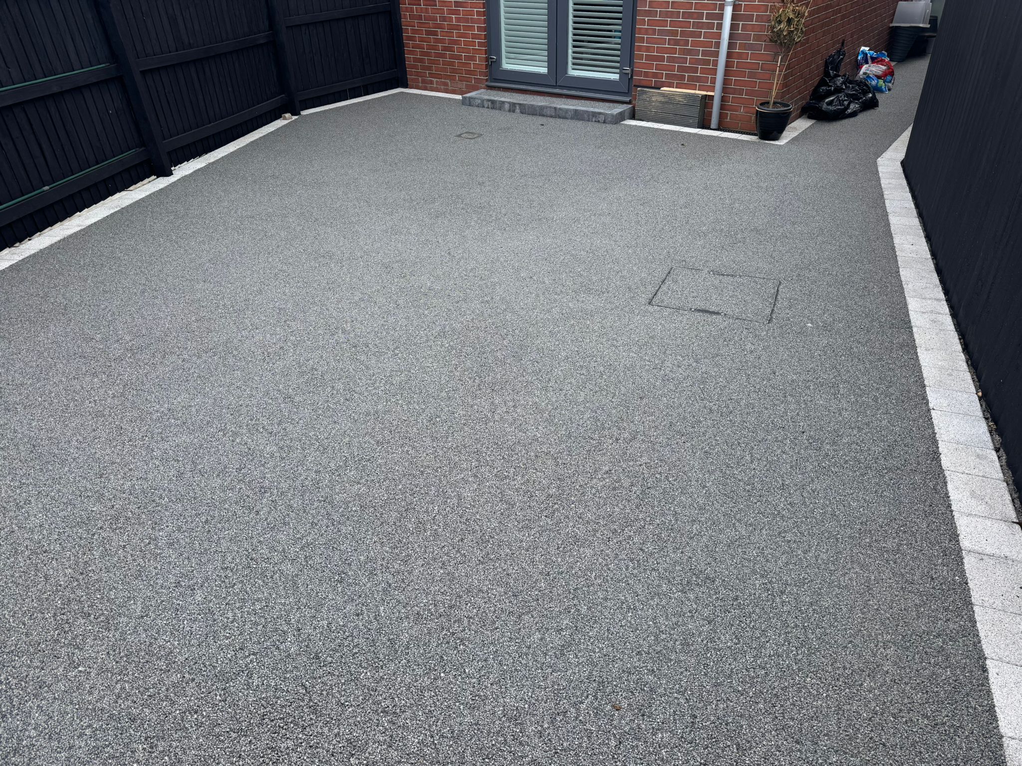Grey resin patio surface with block border and recessed covers