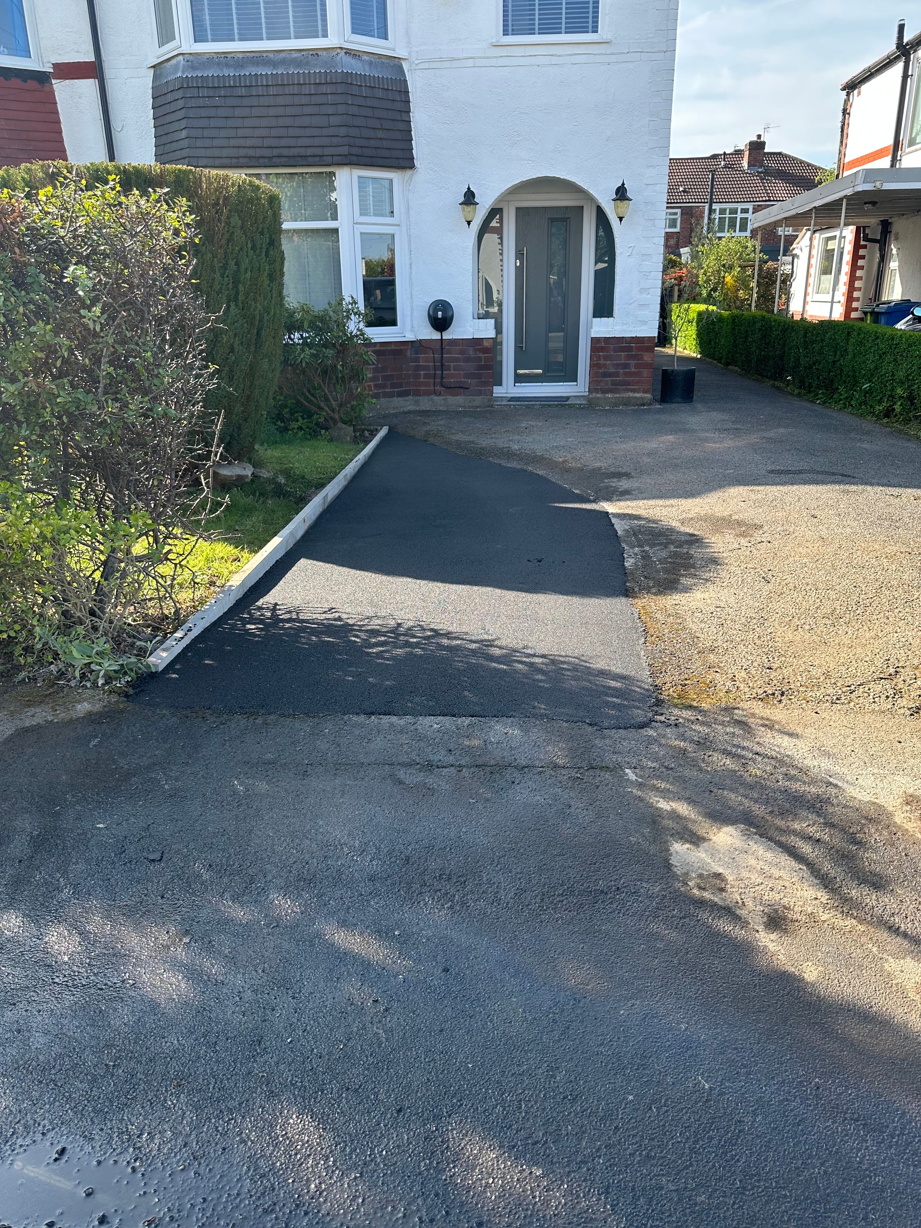 Fresh black tarmac patch on residential driveway — North West England