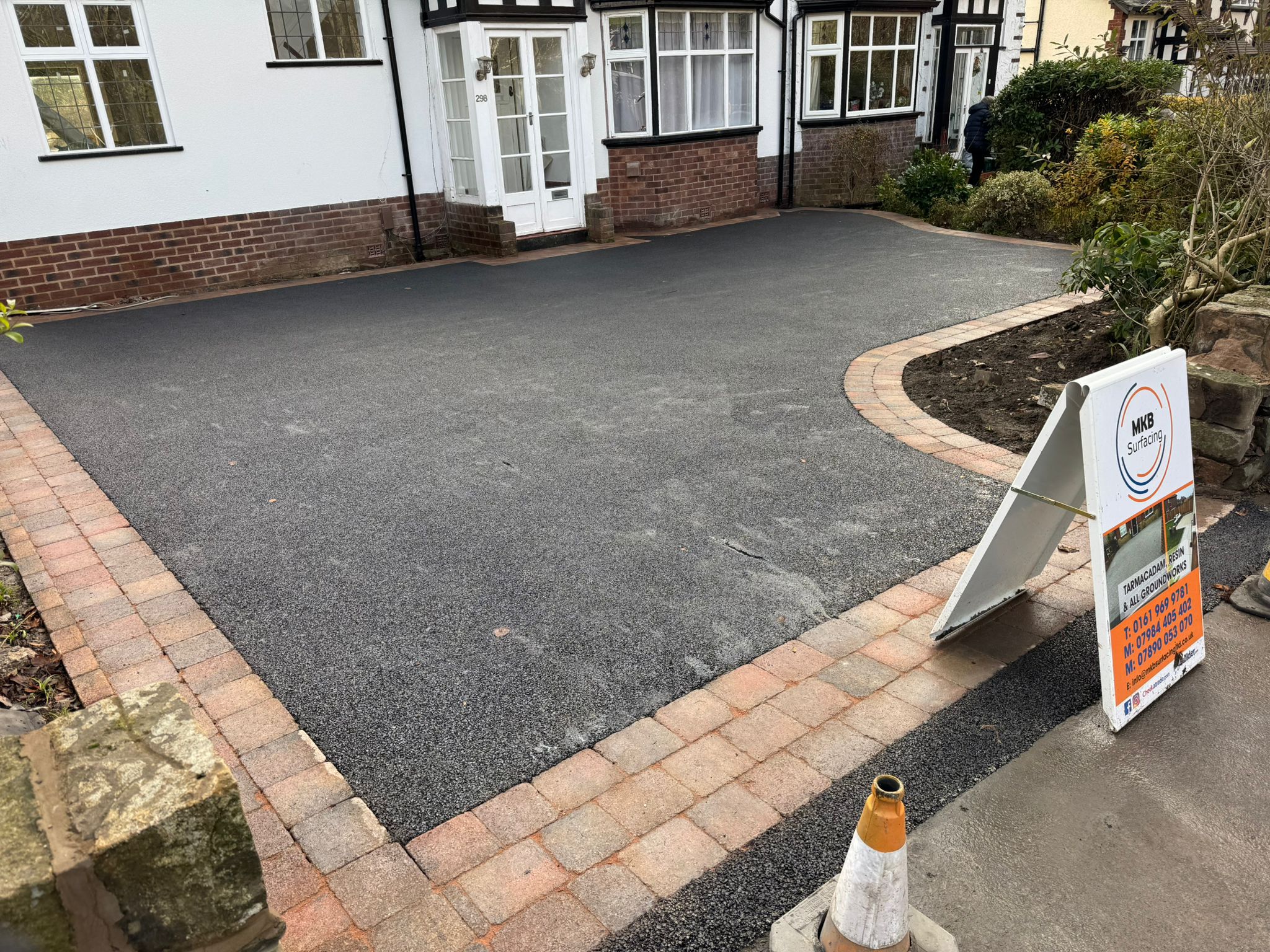 Dark tarmac driveway with decorative block border and MKB Surfacing sign