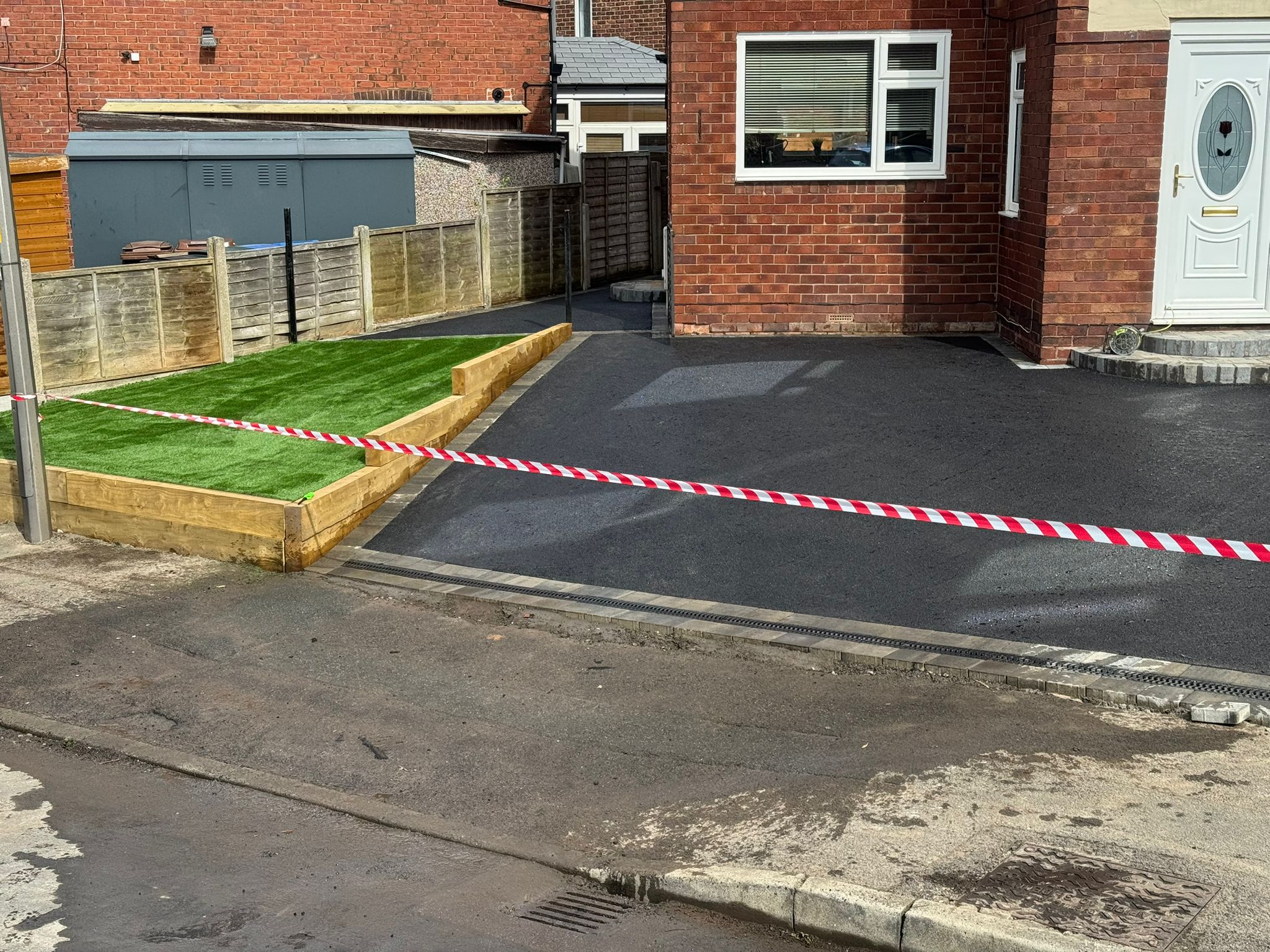 Tarmac driveway with artificial grass and caution tape (alternate angle) — Greater Manchester