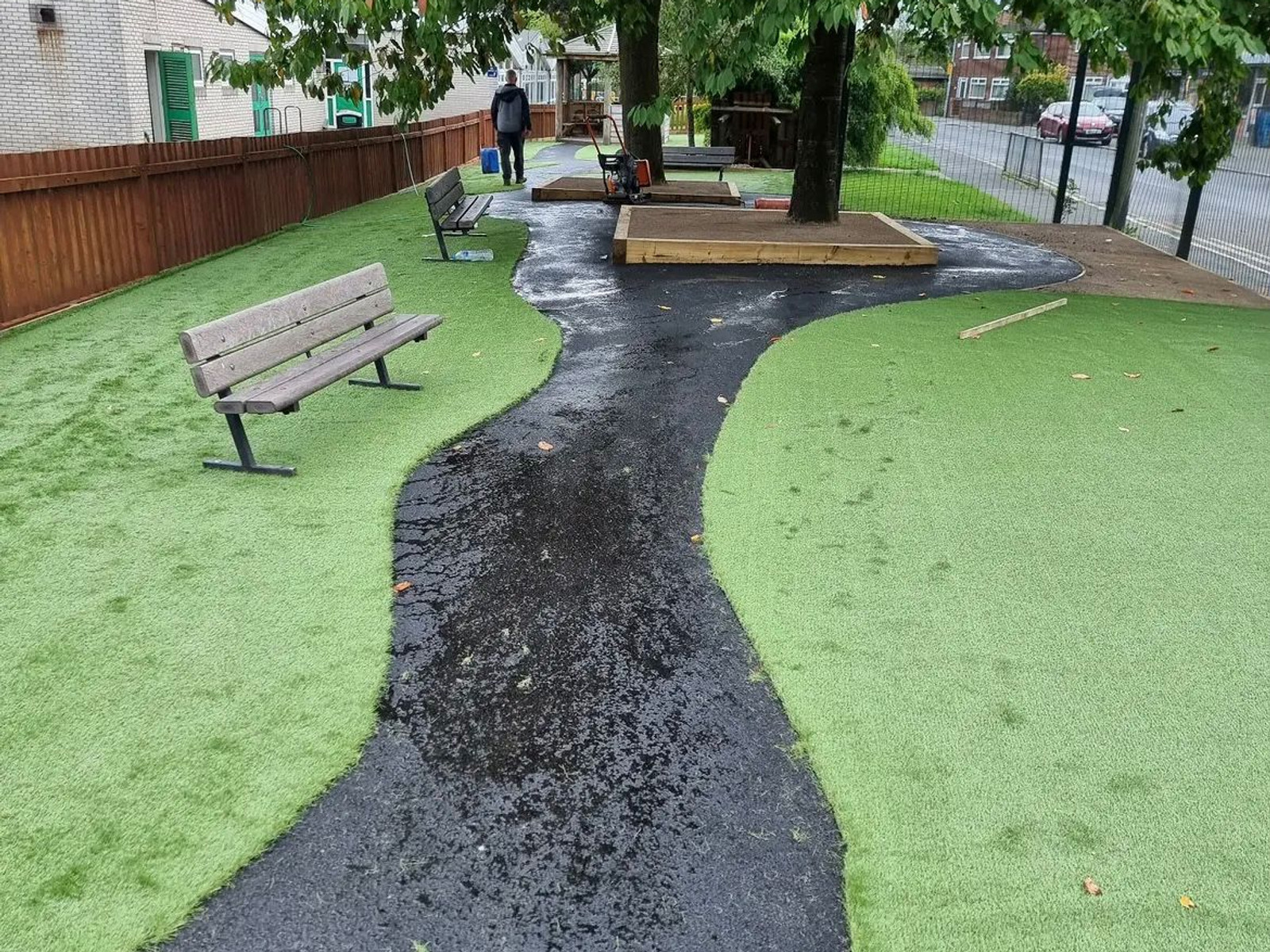Winding tarmac path through artificial grass with benches and tree planters — Cheshire