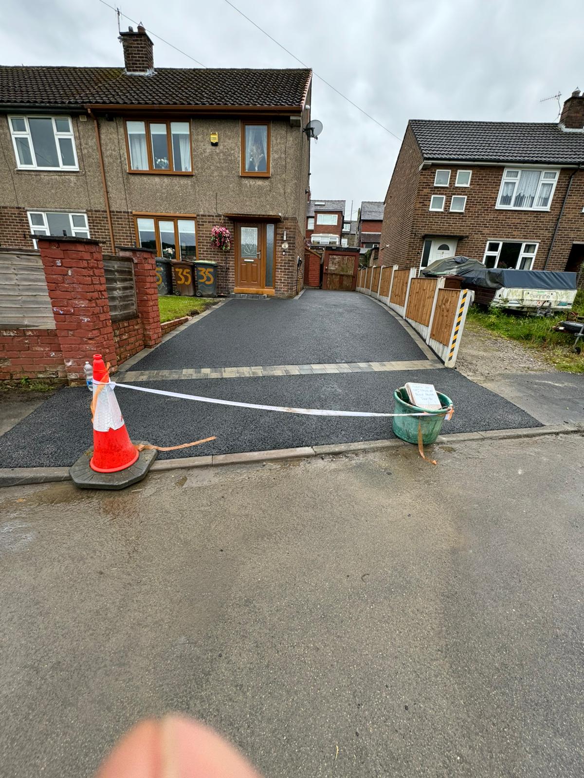 Fresh tarmac driveway with block strip, cone and caution tape at house 33 — Greater Manchester
