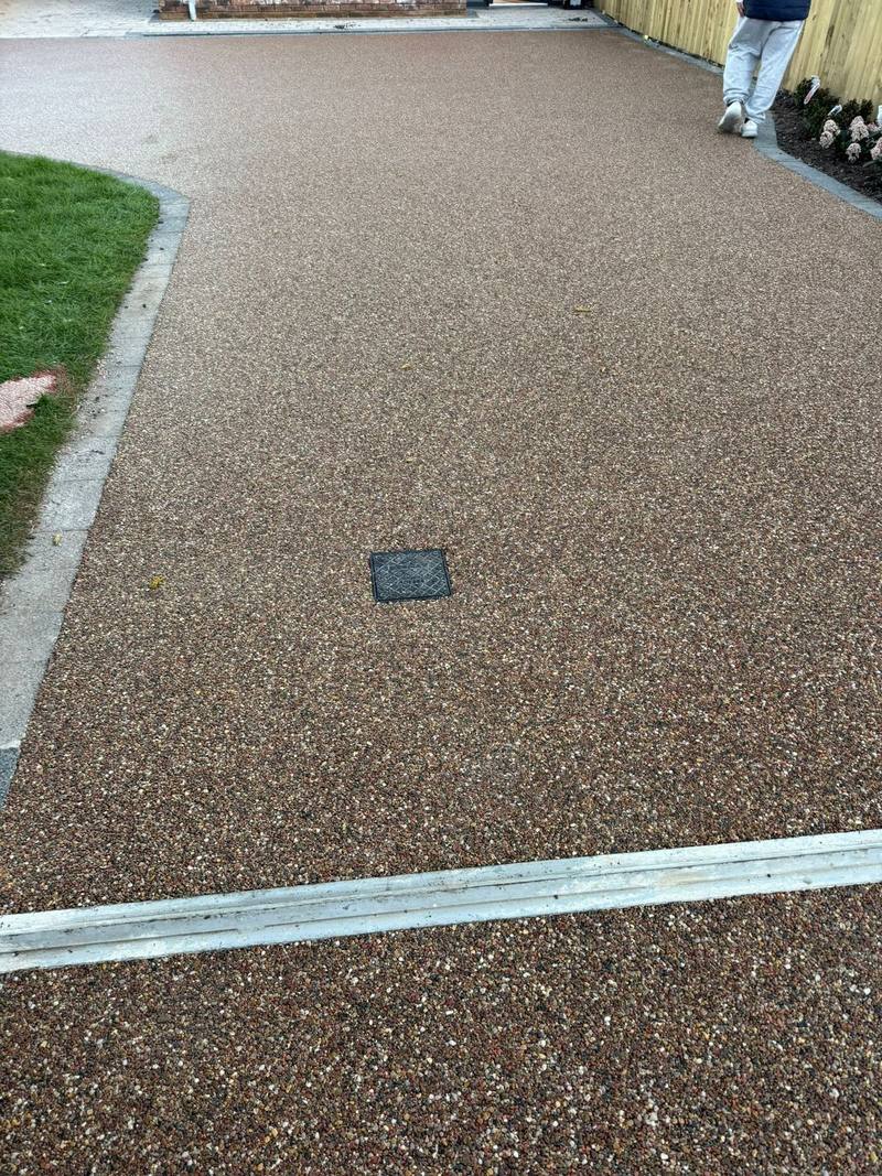 Resin-bound driveway close-up with a recessed manhole cover