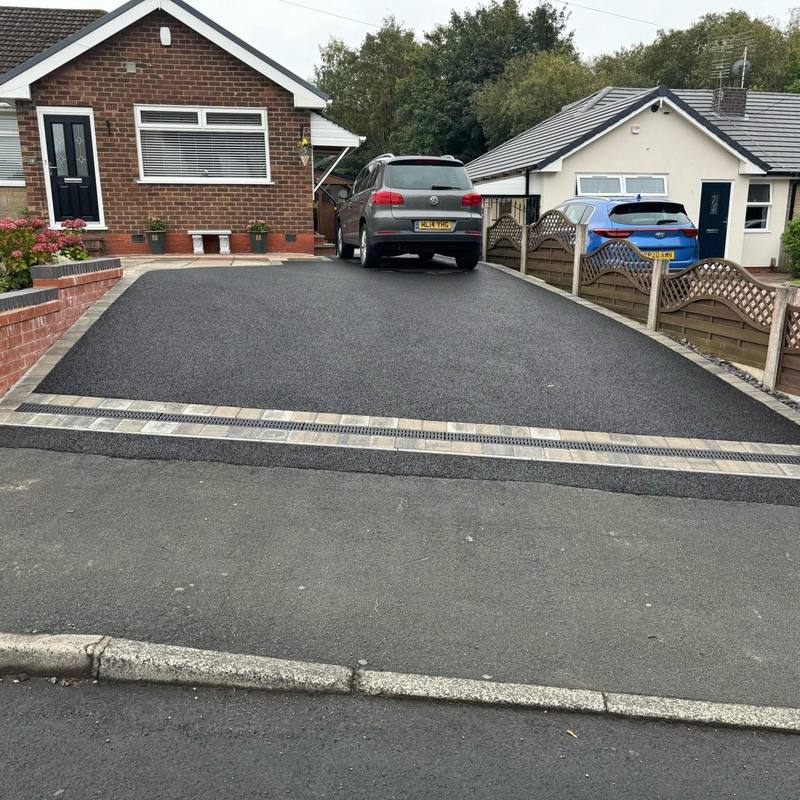 Sloping tarmac driveway with block drainage channel and light block border
